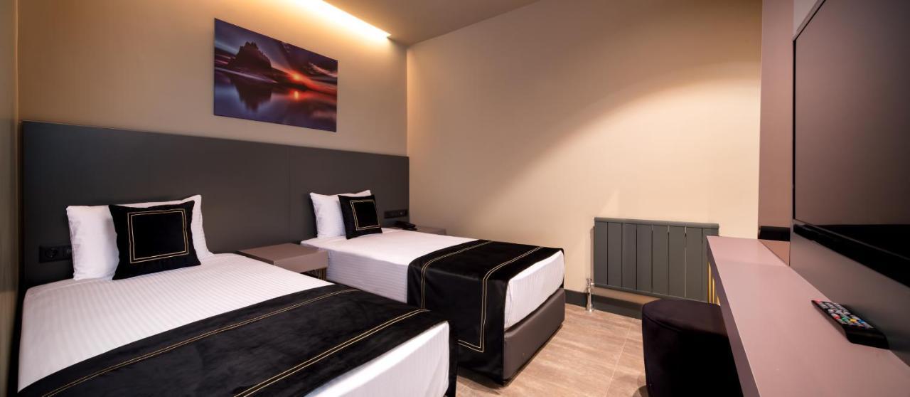 Menalo Hotel Premium Istanbul Airport Exterior photo The photo shows a hotel room featuring two separate beds, each made with white linens and topped with black bedspreads. The decor is modern and minimalist, with a neutral color scheme. There's a piece of artwork on the wall above the beds, depicting 