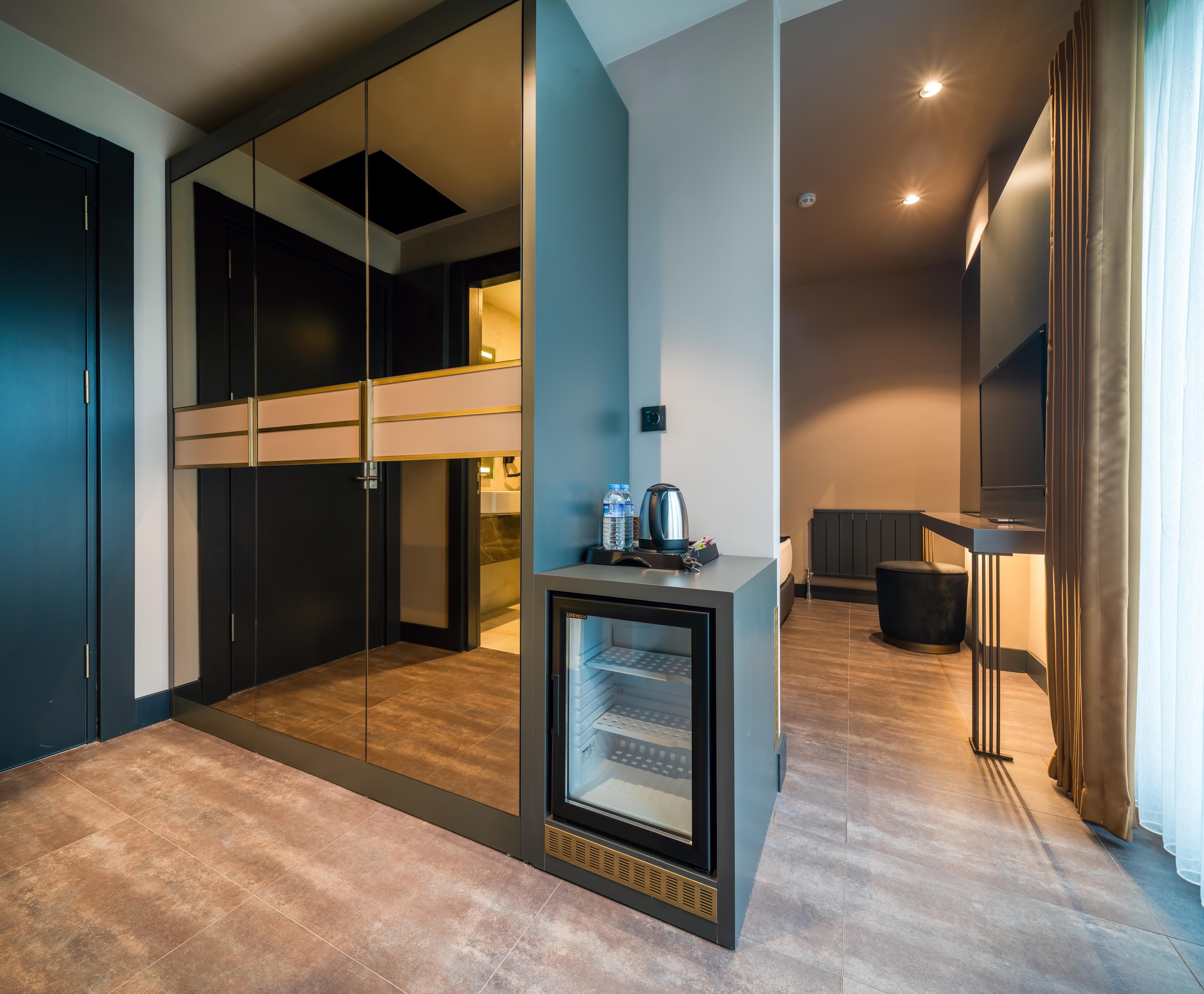 Menalo Hotel Premium Istanbul Airport Exterior photo The photo shows a modern interior space that appears to be part of a hotel room or a high-end apartment. On one side, there is a set of sleek, dark wardrobes with mirrored doors. Next to the wardrobes, there is a small bar area or mini-fridge with a 